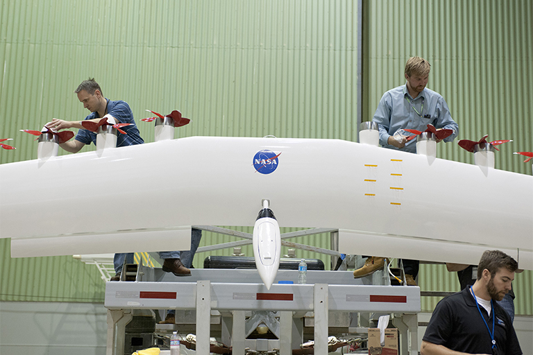 Engineers work on a wing with electric motors that is part of an integrated experimental testbed. From left are Sean Clarke, left, Kurt Papathakis at upper right and Anthony Cash in the foreground. Credit: NASA Photo/Tom Tschida.