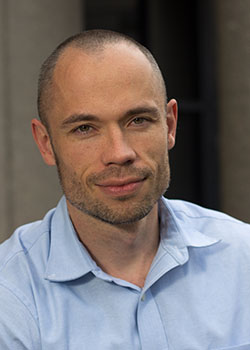 Portrait photo of a man with a slight smile and a shaved head.