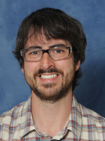 Portrait photo of a smiling man in glasses and a plaid shirt.