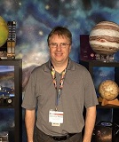 Photo of a man standing in front of a planetary backdrop.