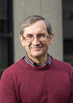 Portrait photo of a smiling man wearing glasses and a burgandy sweater
