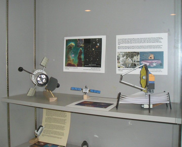 A "John Jogerst modification" paper model of the James Webb Space Telescope shown on the right. A Hubble Space Telescope model is also shown on the left, as well as two other unidentified spacecraft models.