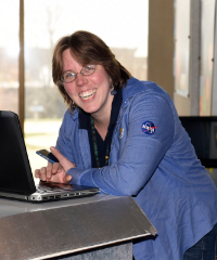 Photo of a smiling woman leaning on a desk