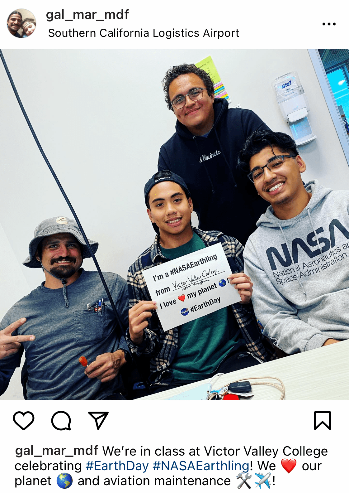 Mockup example of Facebook post with a picture of four young men in an office holding a sign that says "I'm a NASAEarthling from Victor Valley College. I love my planet. Earth Day"