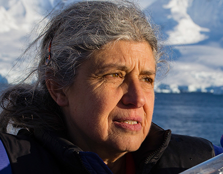 Portrait photo of a woman with grey hair and the ocean and an iceberg in the background