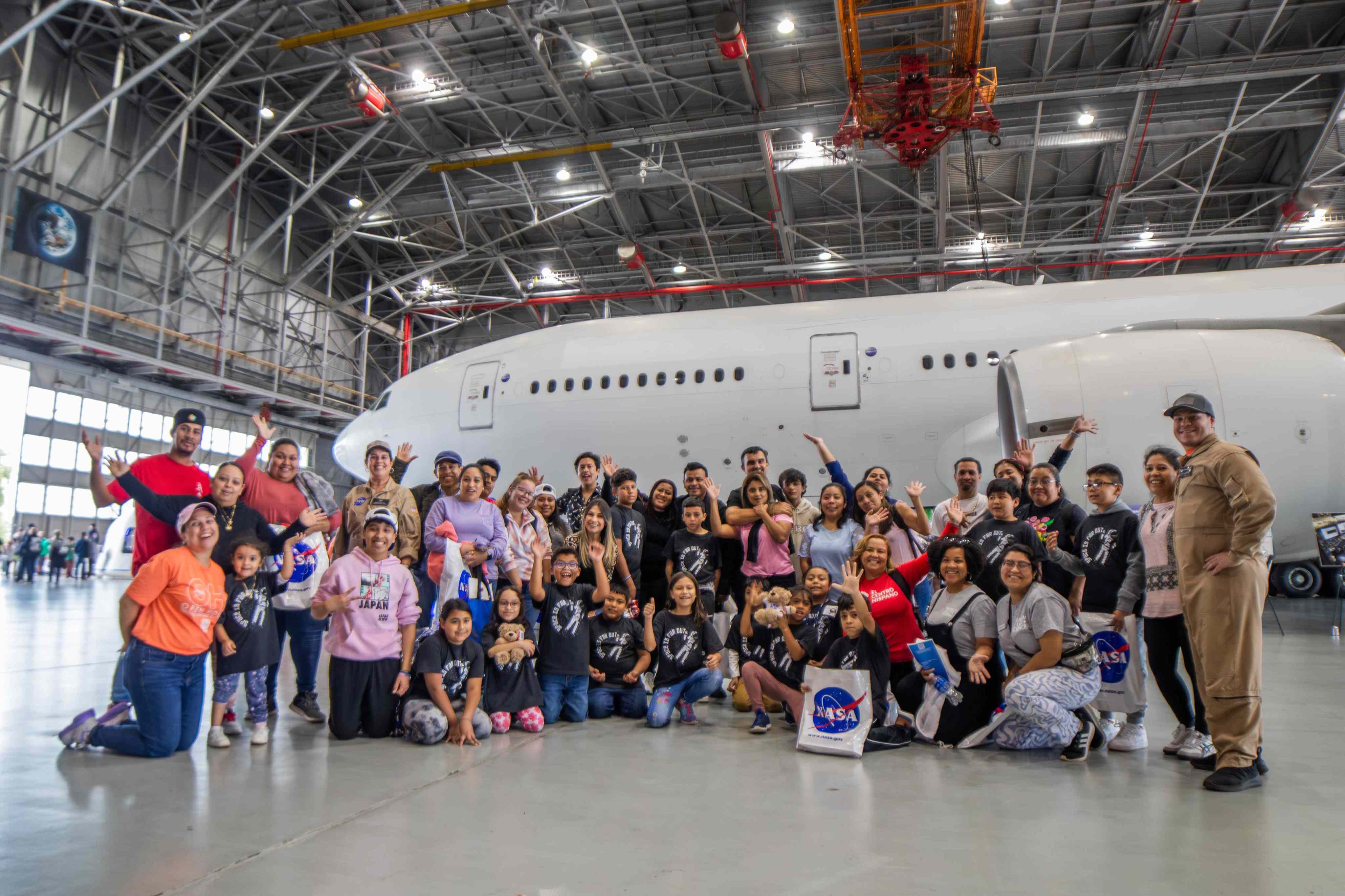 Multiple groups of families standing together in front of an airplane.