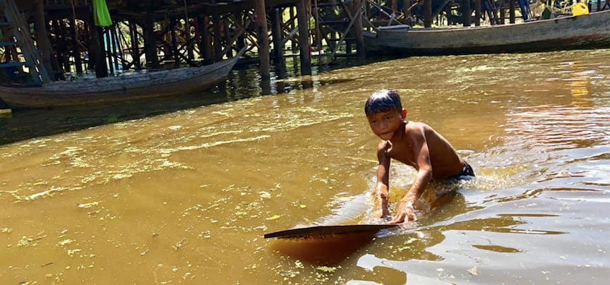 A boy swimming in a floating village on Tonle Sap Lake, Cambodia.