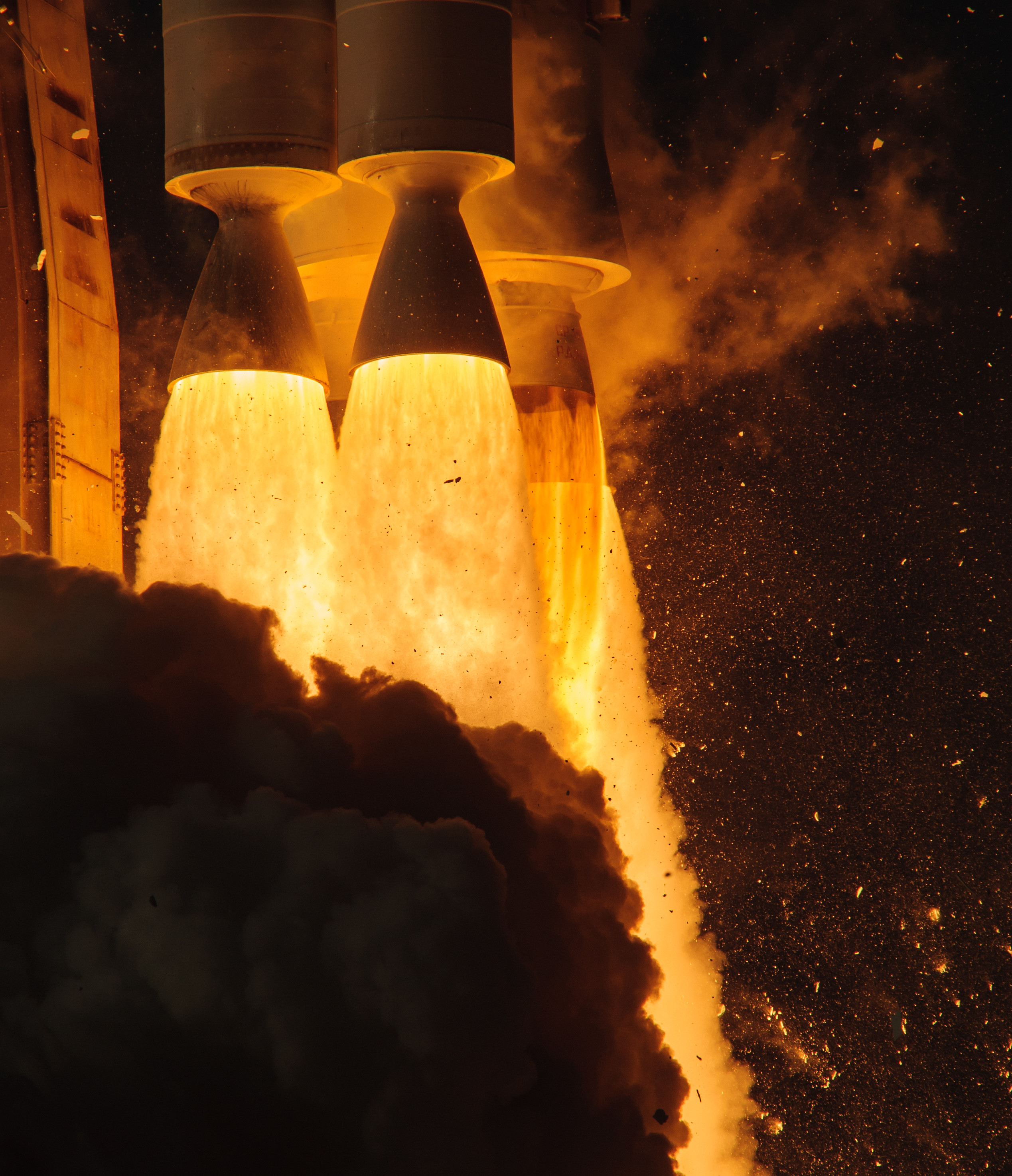 A close-up view of the 4 first-stage engines blasting out an orange firey thrust against a black background.