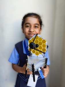 Young girl holding a JWST model she built