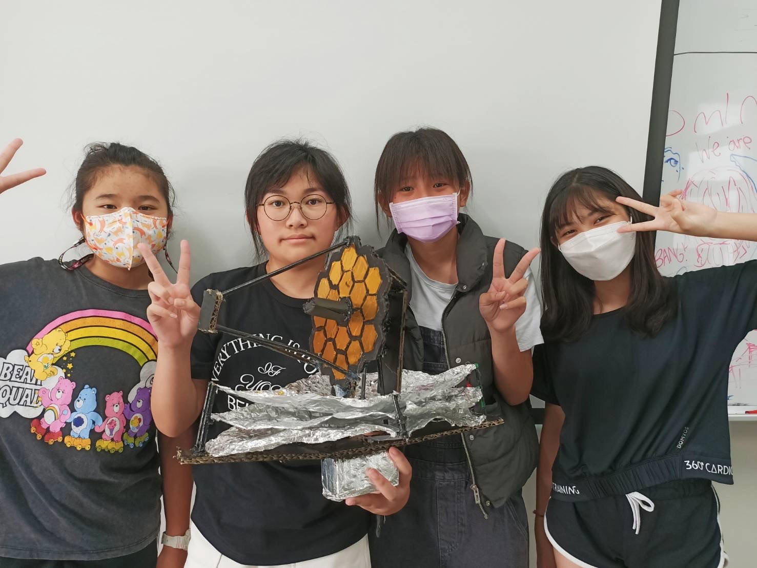 Image of four young ladies holding a model of JWST they built