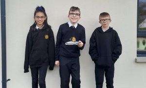 Three young Scottish students holding the JWST model they built.