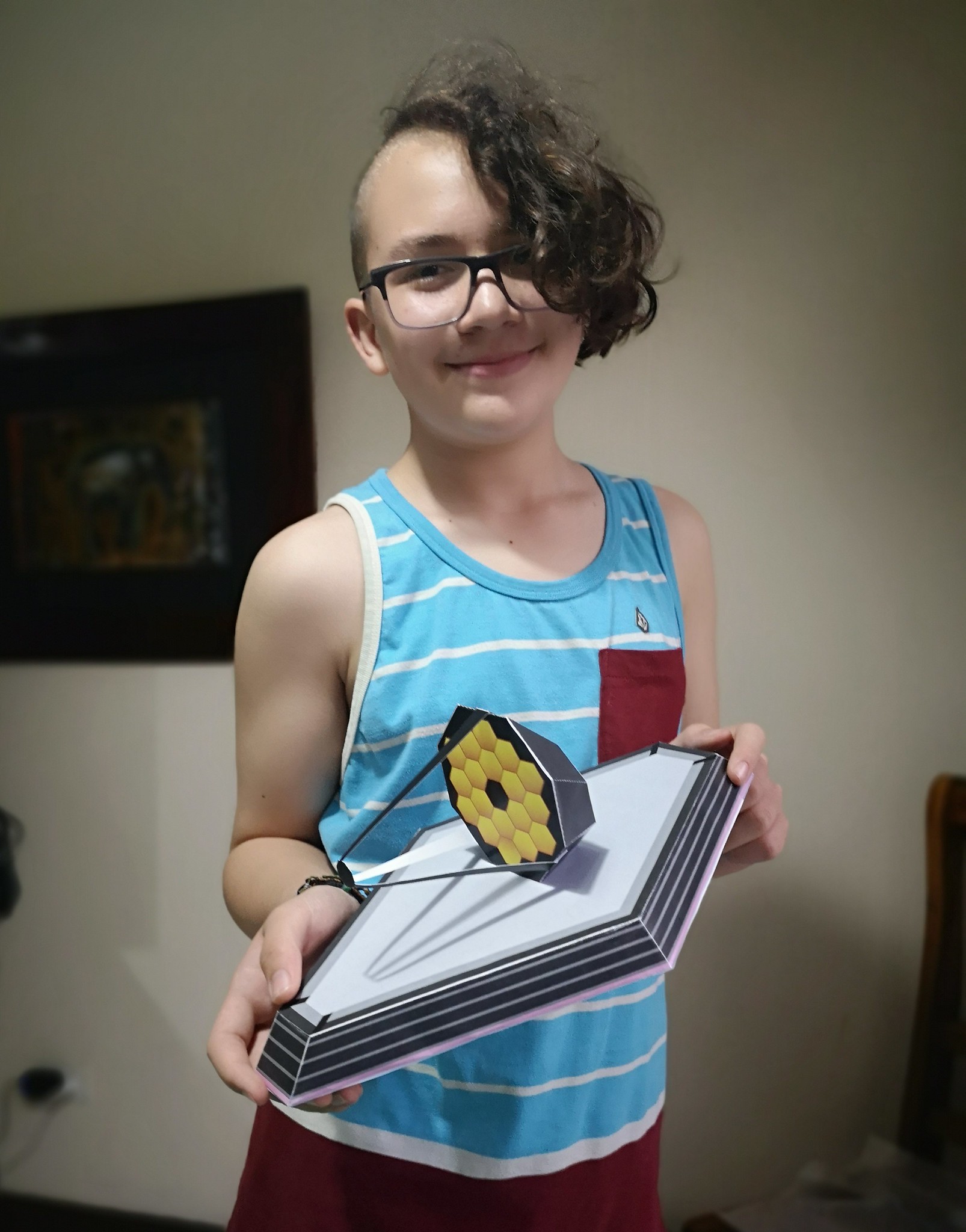 Image of a young girl holding a model of JWST she built