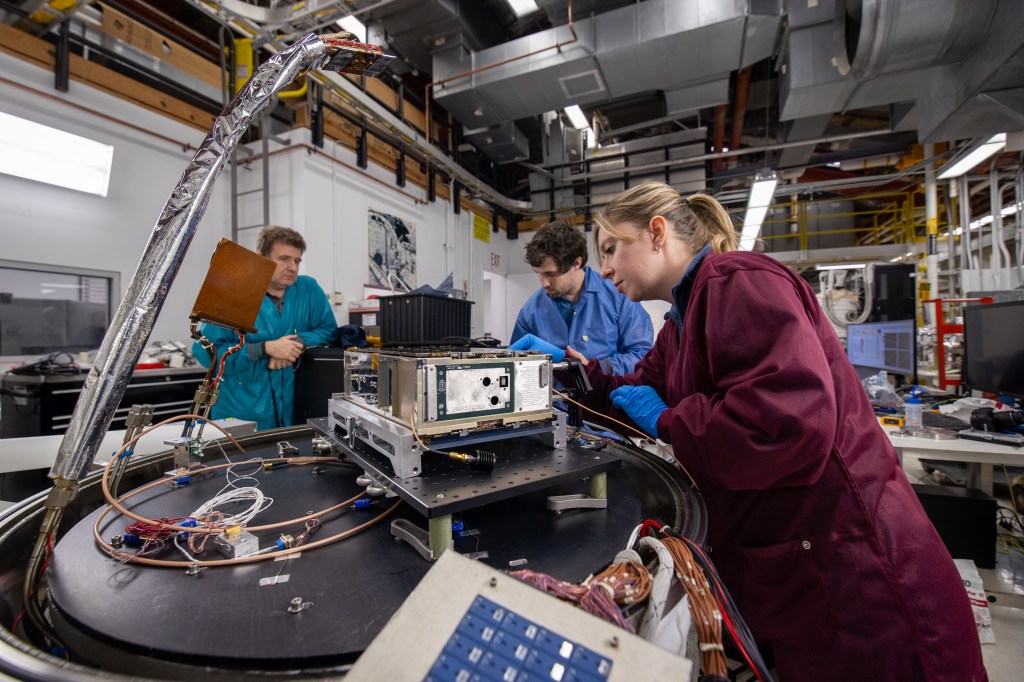 This photograph shows two people working on the BurstCube satellite.