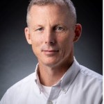 head shot of short-haired man in white button-down shirt