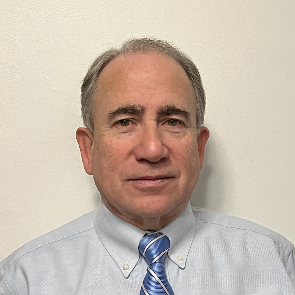 Headshot of Dr. Mario R. Perez in a blue tie with white stripes and a light grey dress shirt.