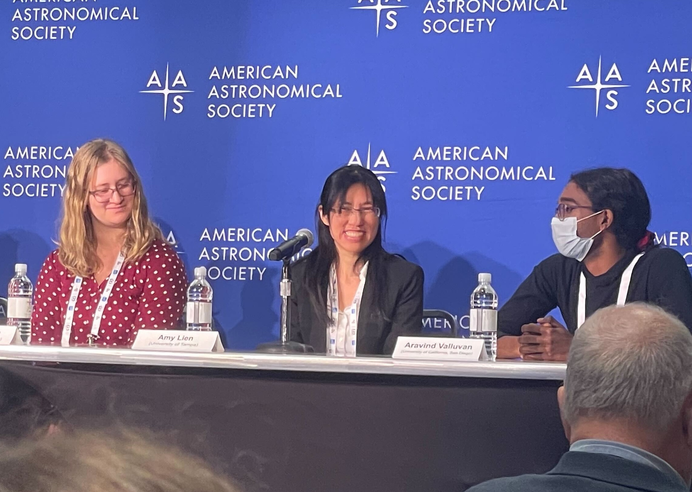 Photo of three women sitting at a press table with a blue background that reads American Astronomical Society