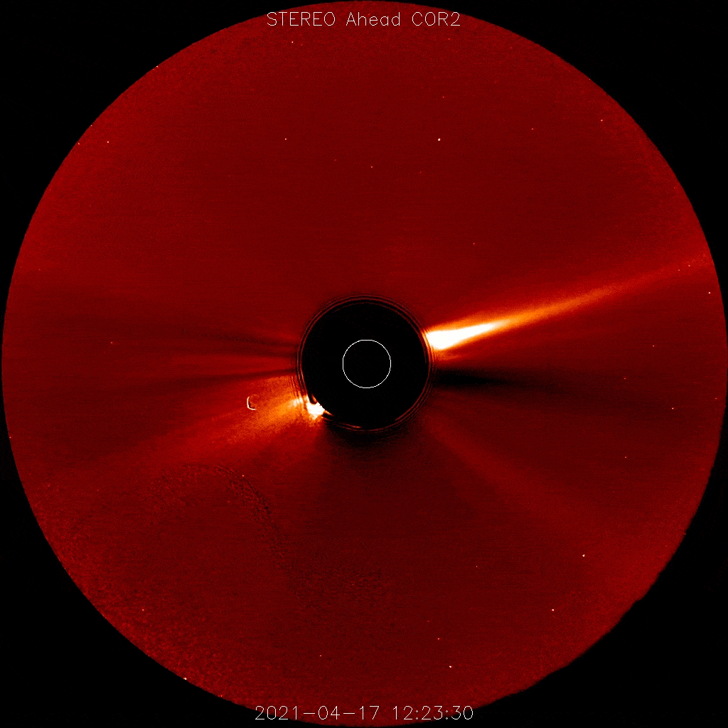 一个动画显示了一团白色的物质从太阳（中心被一个黑色的圆盘覆盖）向图像左侧滚滚而来，背景是红色，有几十颗星星。顶部显示“STEREO Ahead COR2”，底部显示日期2021-04-17，时间从12:23:30到23:53:30。