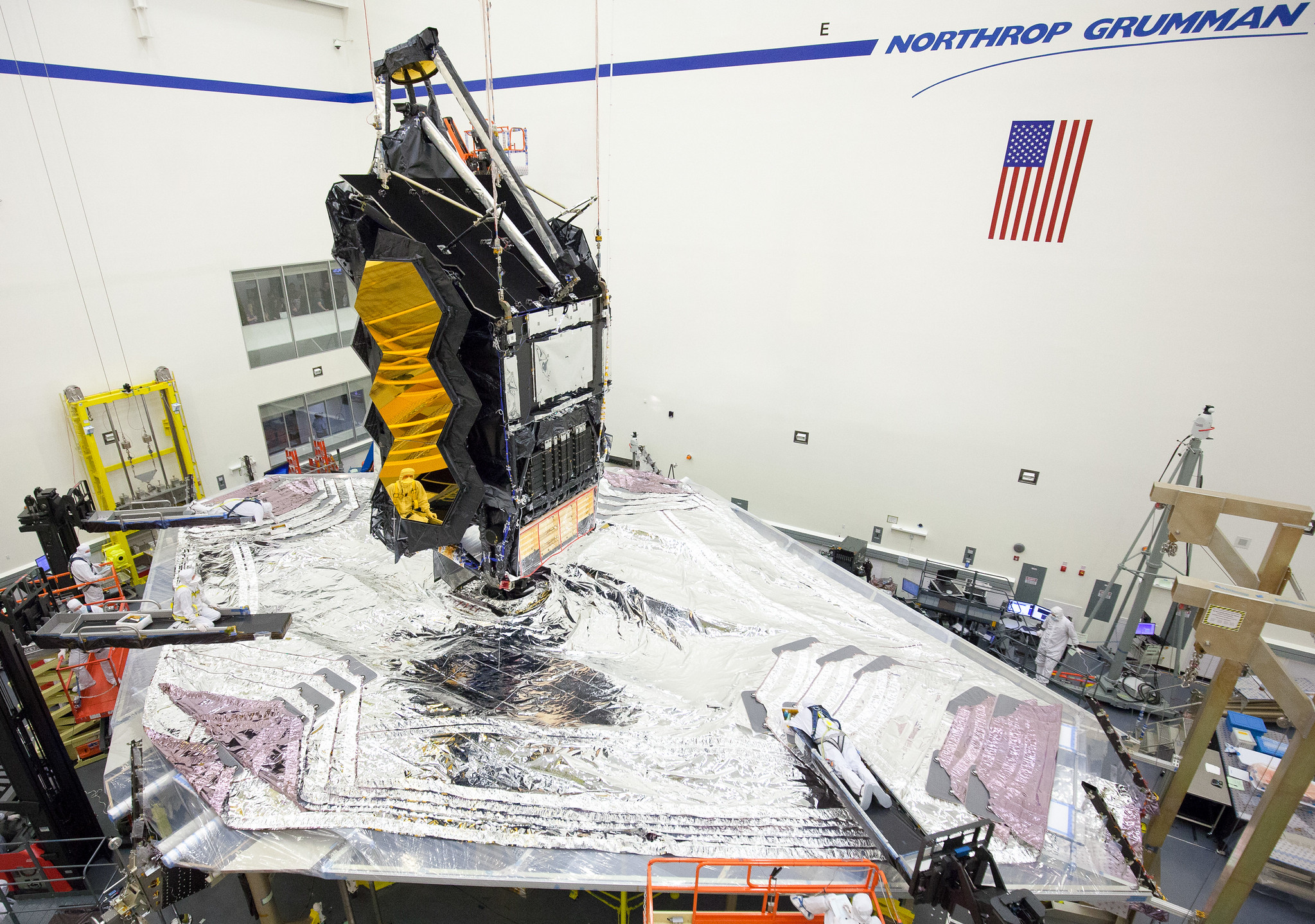 In this photo from August 2020, engineers and techs prep the James Webb Space Telescope for the environmental testing it underwent this fall. This testing, designed to mimic the sound and vibration the telescope will experience during launch, was successfully completed in early October 2020. Here the sunshield is carefully folded in preparation for stowing the telescope into its launch configuration.