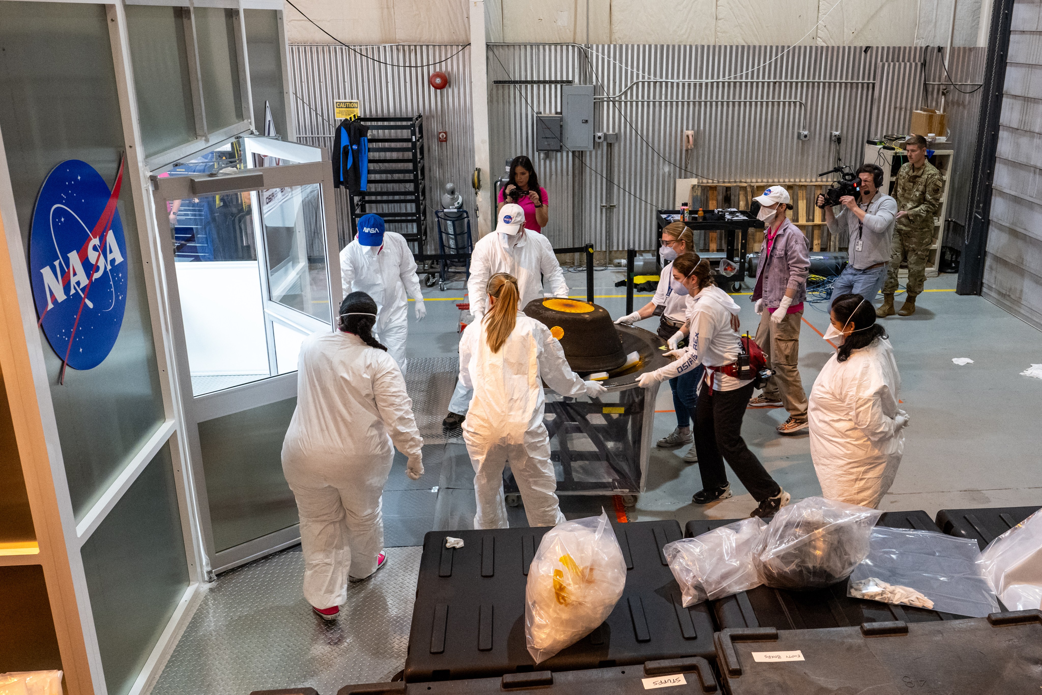 Several people transport the capsule into a temporary cleanroom on a cart