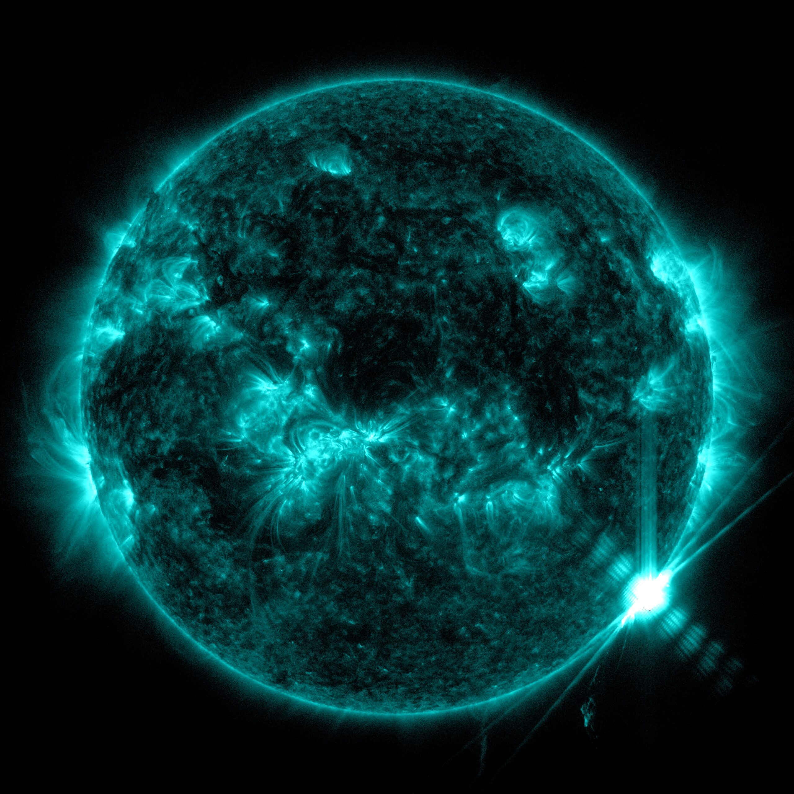 Full image of the Sun against a black background and colorized in a vibrant teal color, which showcases the dynamic beauty of the Sun and highlights areas of activity. The X3.3 flare appears as a bright white flash on the lower right side of the image.