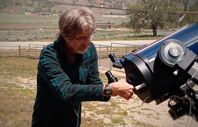 Photo of a man outside maneuvering a large telescope