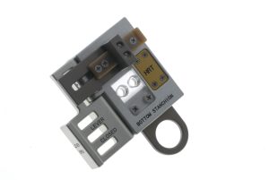 A roughly square-shaped tool with screws, two small holes in a clear window, and a loop-shaped appendage.