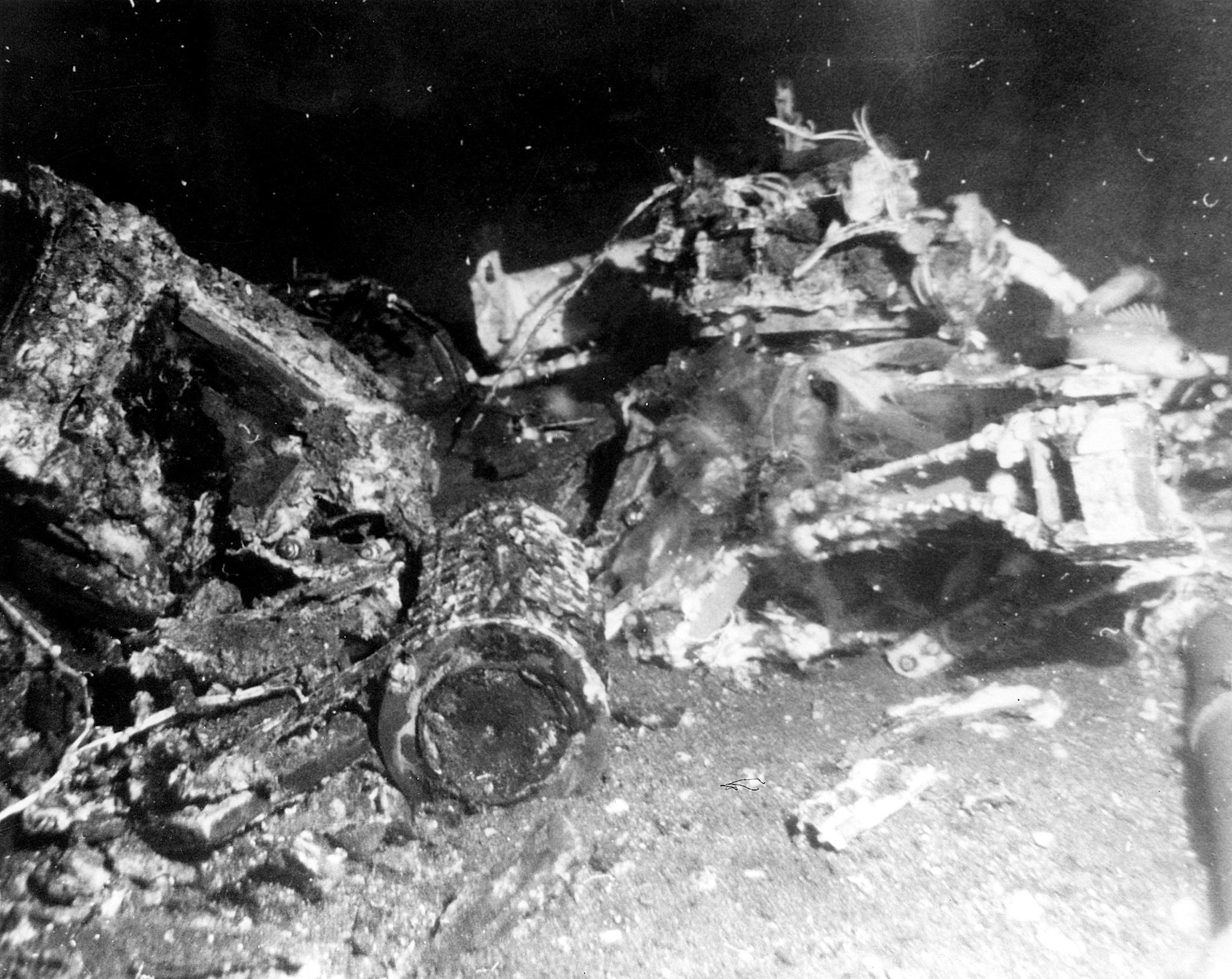 Wreckage on the sea flooer, including a cylinder in the foreground.