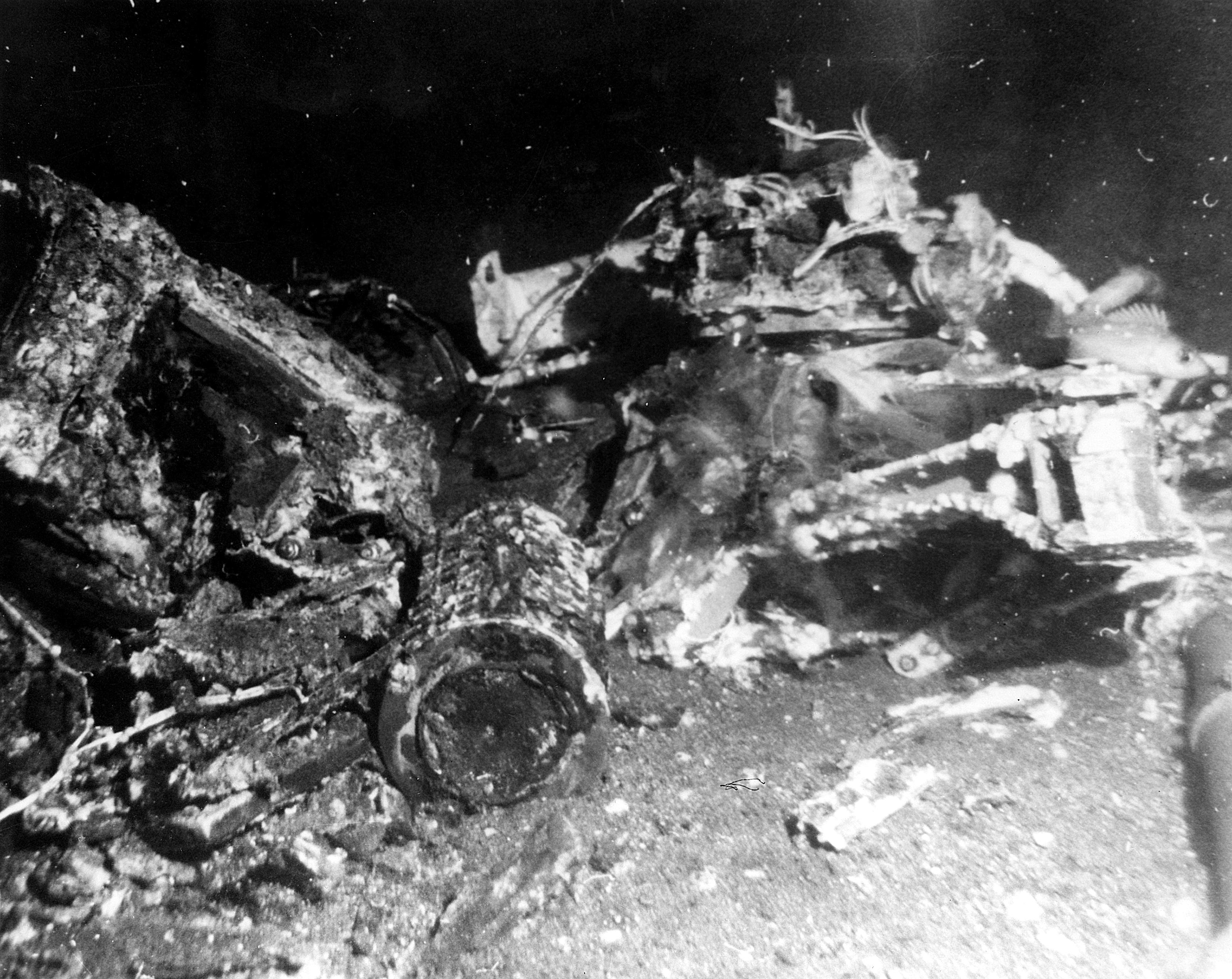 Wreckage on the sea flooer, including a cylinder in the foreground.