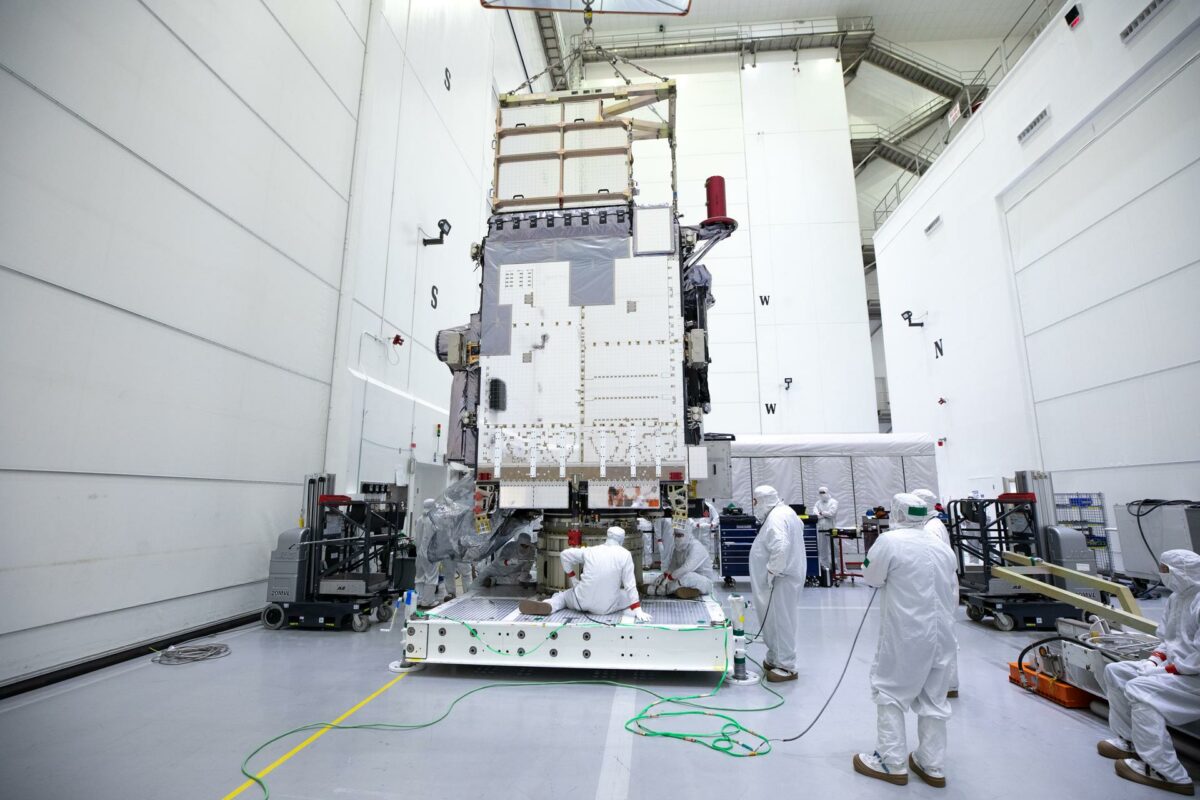 A view of the GOES-U satellite in a clean room being prepped for launch with technicians in full clean room white "bunny suits" working.