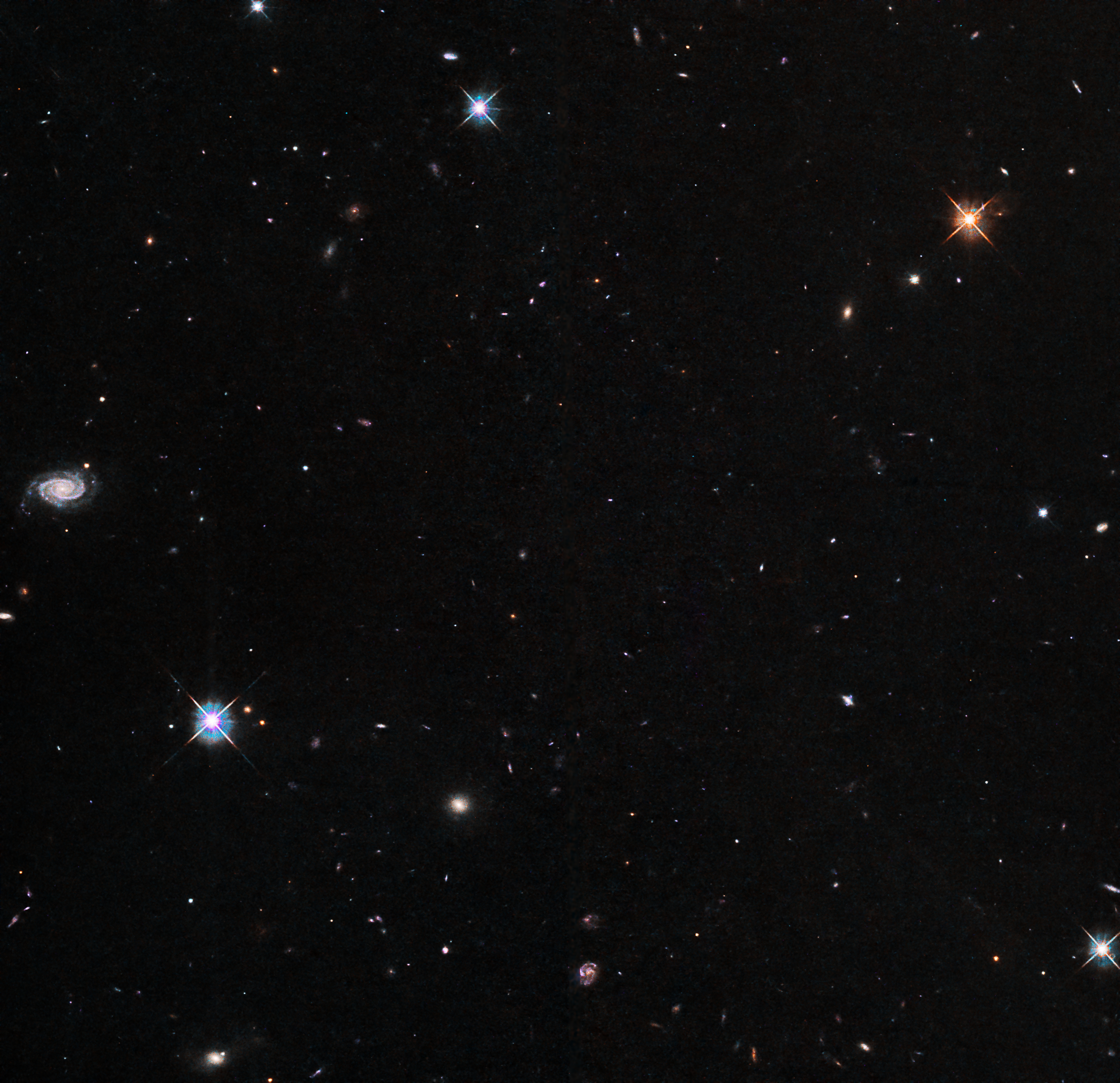 Several bright stars and many background galaxies are visible against a black background.