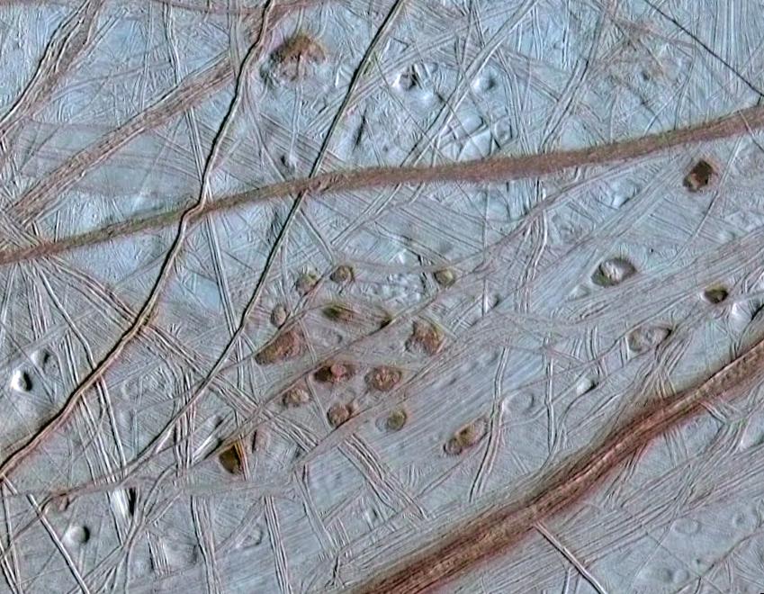 The icy terrain of Europa is crisscrossed by reddish stripes in this view from above.