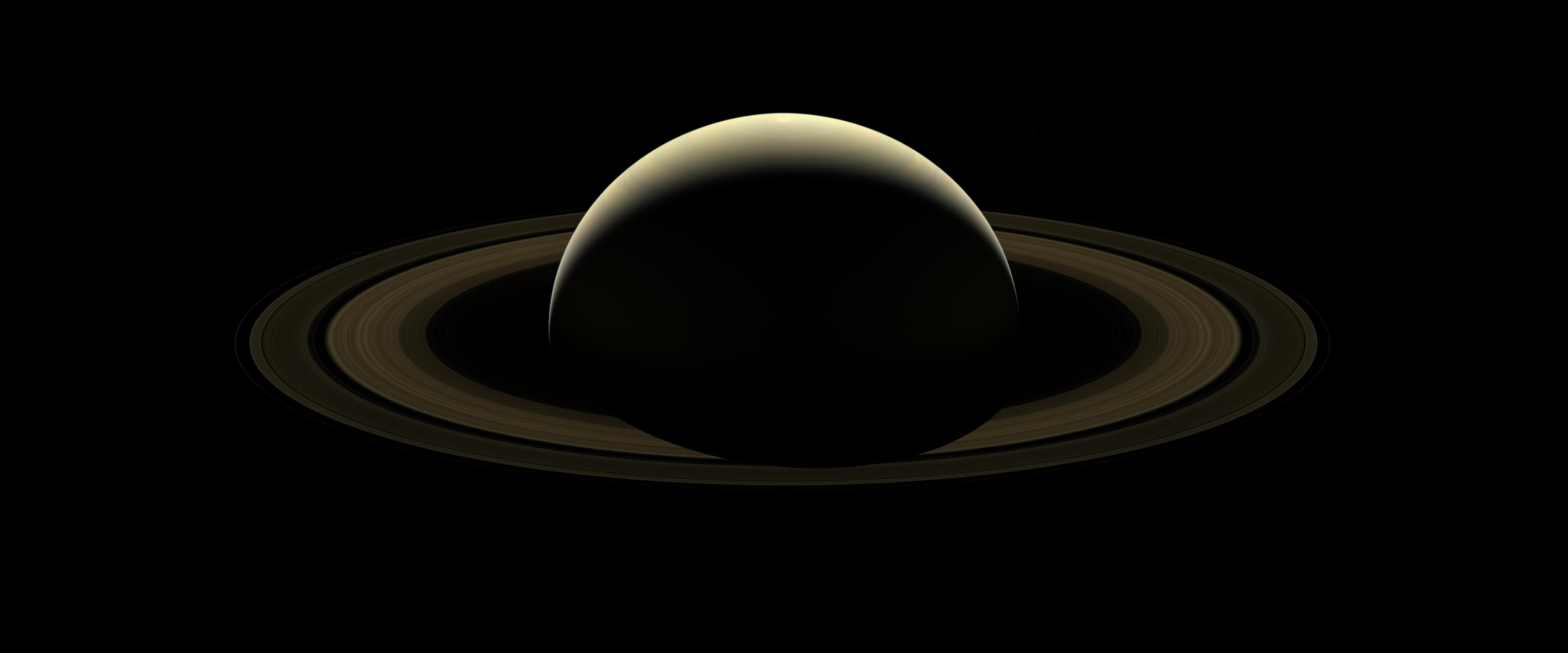 Magestic Saturn and its rings are barely illuminated view of the entire planet.
