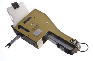 A gold-colored device with a handle and a short, thin, forked protrusion.