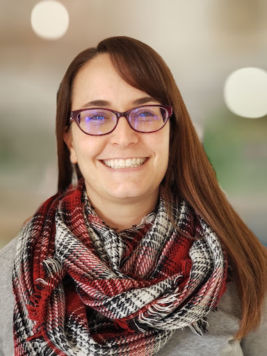 Portrait photo of a smiling woman with long hair and glasses.