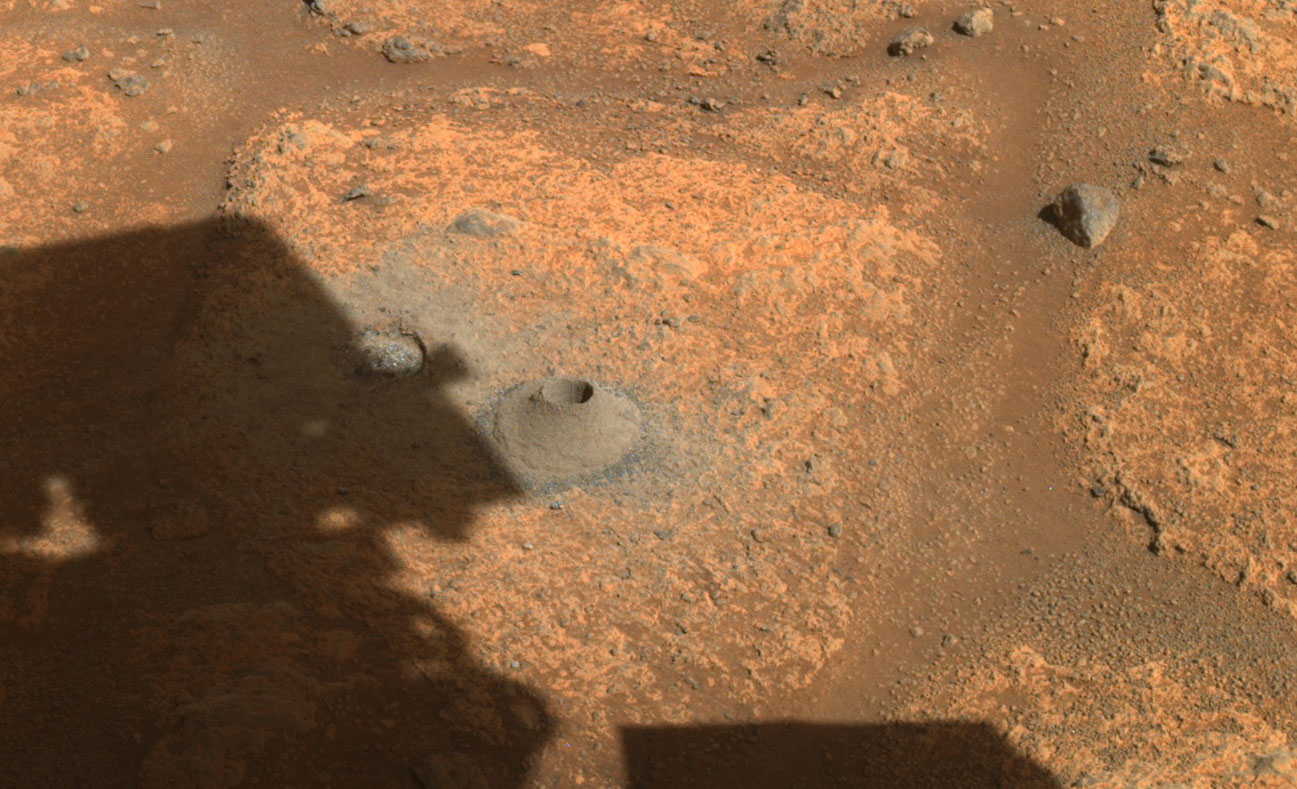 This is a colored image of Perseverance's shadow exploring the rocky and sandy surface of Mars.