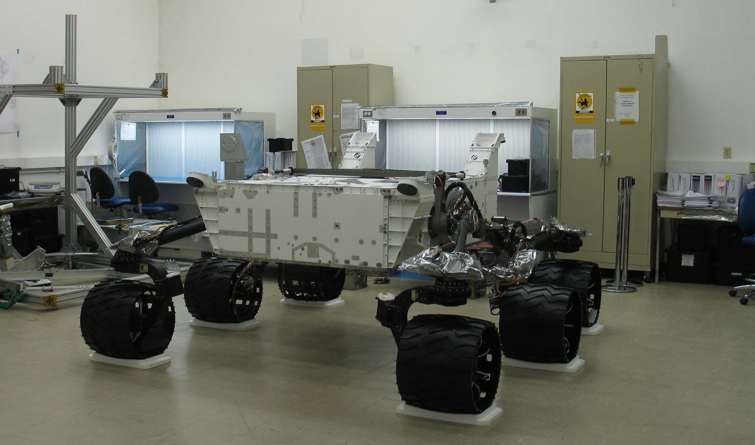 This image shows the body of the Mars Science Laboratory rover inside a clean room, supported by its six huge wheels and suspension system. Specially fitted platforms underneath the wheels hold the rover in place and prevent it from moving.