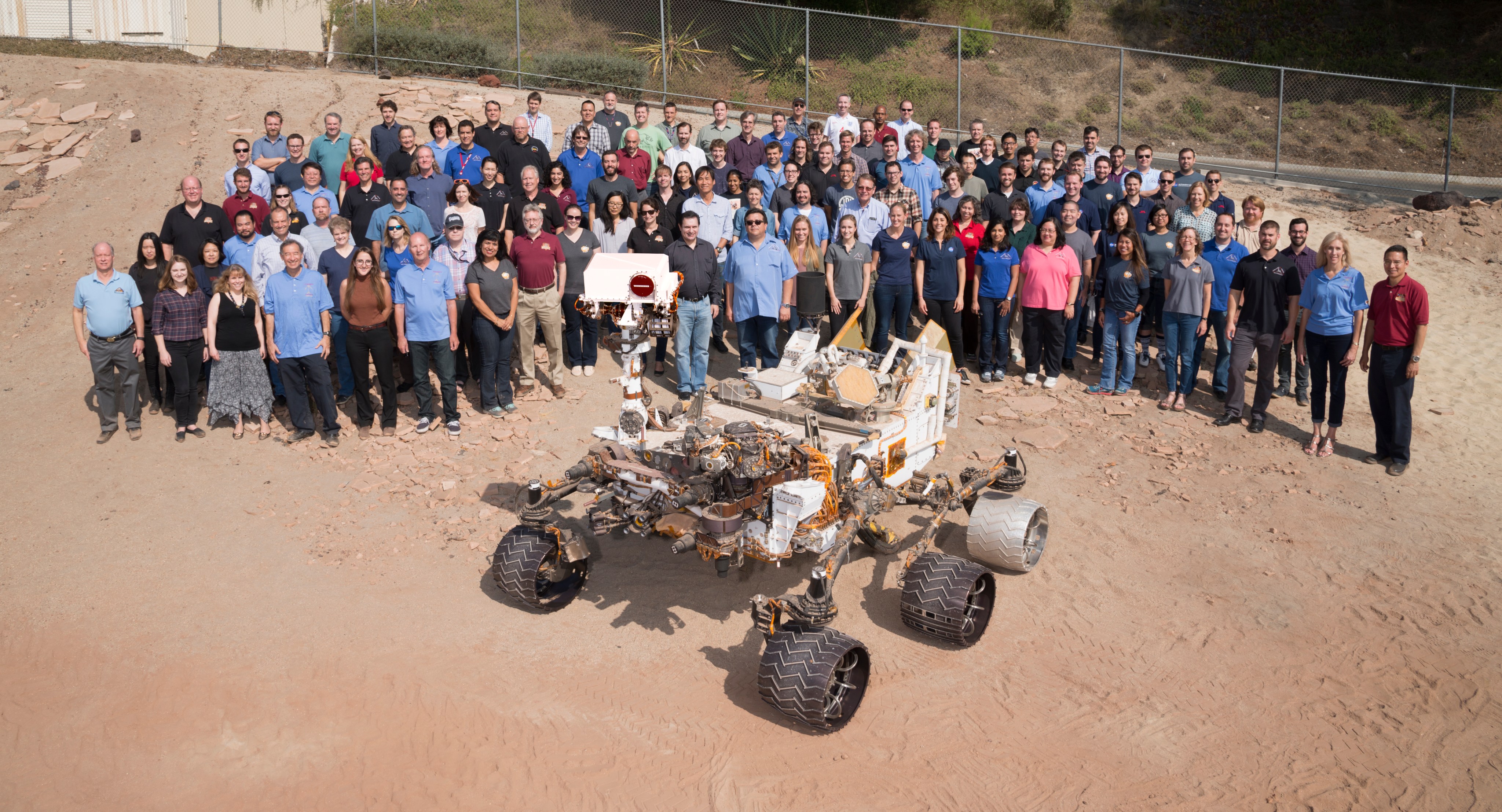 Many members of NASA's Mars Science Laboratory Project, which operates the Curiosity rover on Mars, gathered for this 2016 team photo with a test rover in the "Mars Yard" at NASA's Jet Propulsion Laboratory, Pasadena, California.