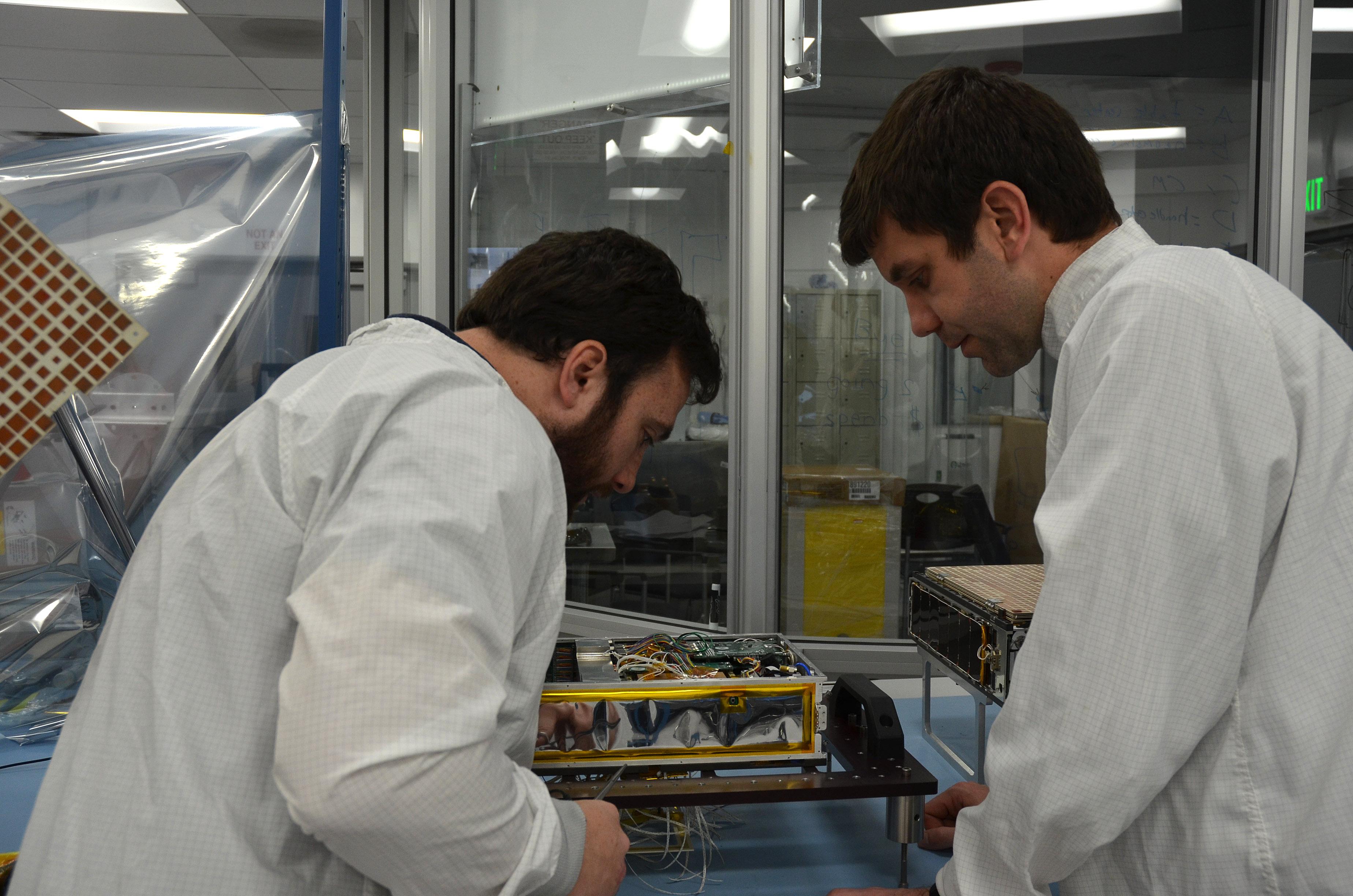 Engineers for NASA's MarCO (Mars Cube One) technology demonstration inspect one of the two MarCO CubeSats. Joel Steinkraus, MarCO lead mechanical engineer, left, and Andy Klesh, MarCO chief engineer, are on the team at NASA's Jet Propulsion Laboratory, Pasadena, California, preparing twin MarCO CubeSats.