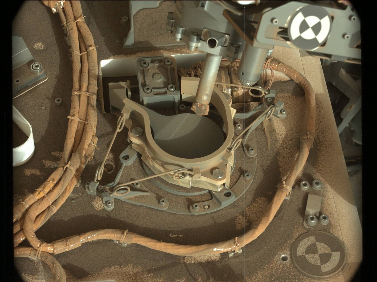 The drill bit of NASA's Curiosity Mars rover over one of the sample inlets on the rover's deck. The inlets lead to Curiosity's onboard laboratories. This image was taken on Sol 2068 by the rover's Mast Camera (Mastcam).