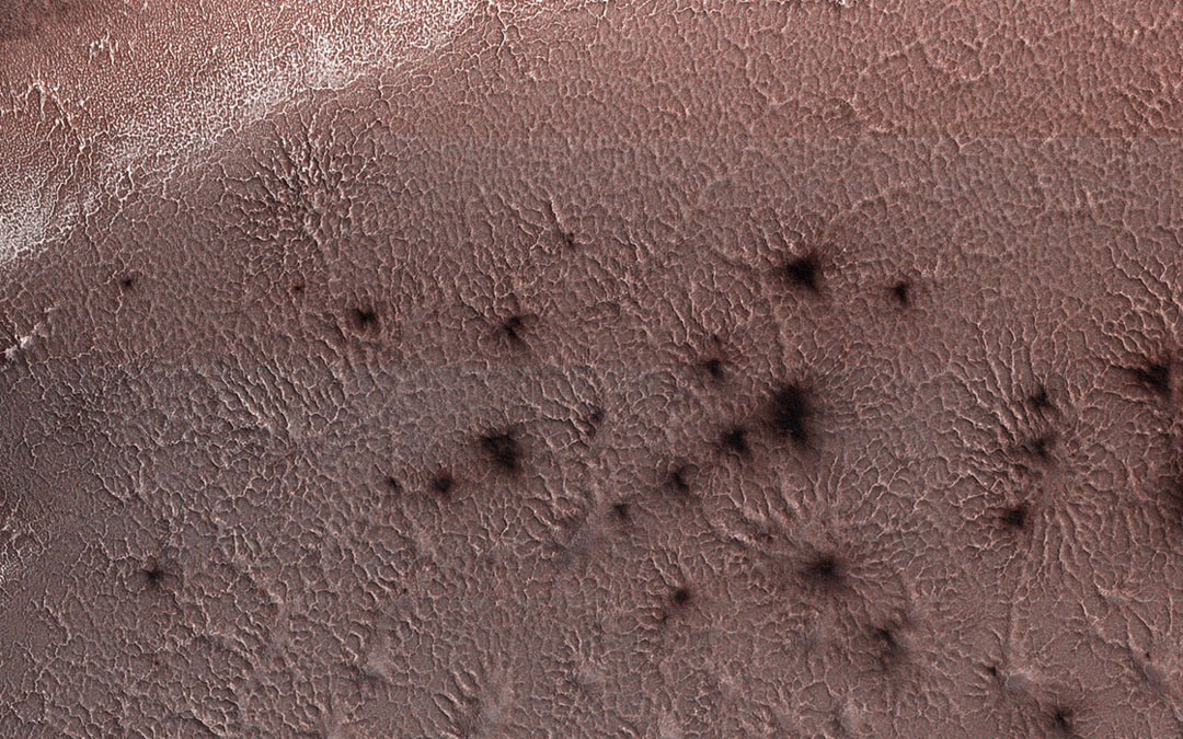 This image from NASA’s Mars Reconnaissance Orbiter shows spider-like formations at the Martian South Pole. They form when heating from the springtime Sun causes carbon dioxide beneath the surface to change from solid to gas and erupt, leaving dust behind.