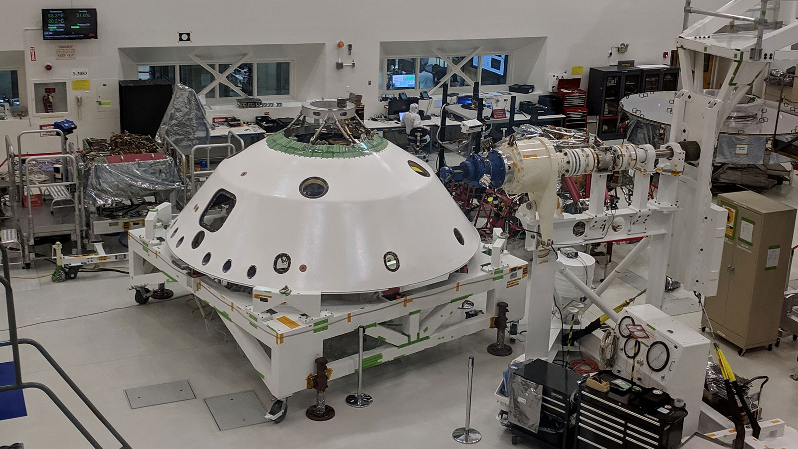 The backshell that will help protect the Mars 2020 rover during its descent into the Martian atmosphere visible in the foreground. A technician on the project monitors the progress of Systems Test 1.