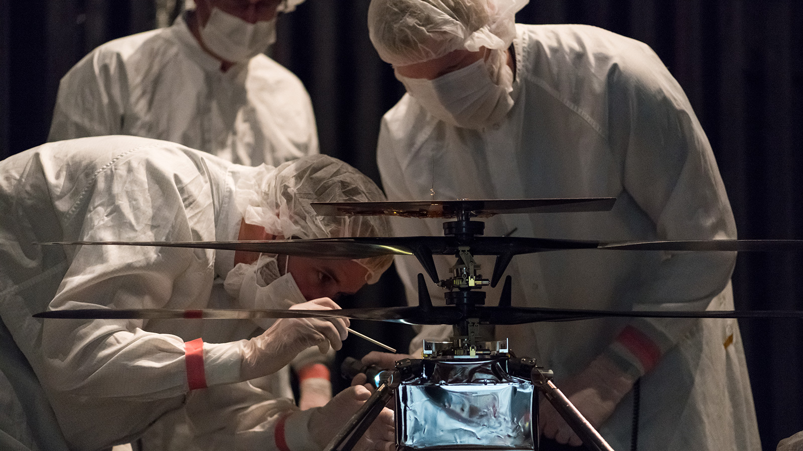 Members of NASA’s Mars Helicopter team attach a thermal film enclosure to the fuselage of the flight model.