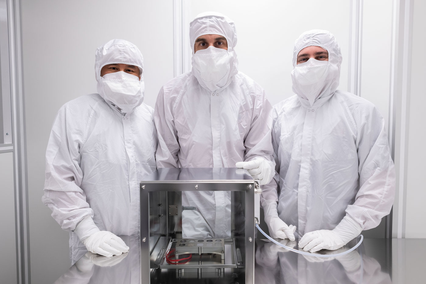 Image of engineers with the Mars 2020 SHERLOC Calibration Target in a clean room at NASA's Johnson Space Center.