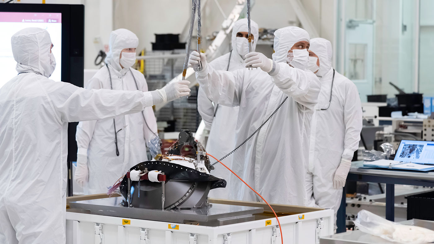 In this image, taken on Aug. 5, 2019, engineers at NASA's JPL  lift the Mars 2020 rover's bit carousel from its storage container. The bit carousel is at the heart of the rover's Sample Caching System.