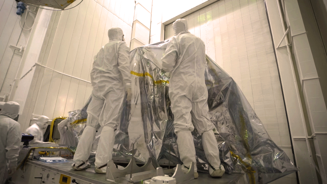 In time-lapse video bunny-suited engineers remove the inner layer of protective foil on NASA's Mars 2020 rover after it was moved to a different building at JPL for testing.