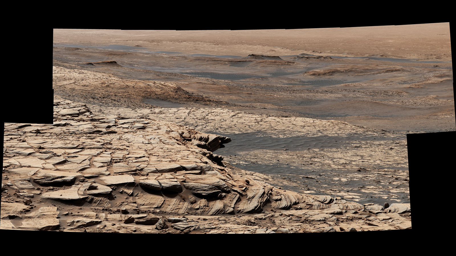 Curiosity Mars rover captured this view from "Greenheugh Pediment." In the foreground is the pediment's sandstone cap. At center is the "clay-bearing unit"; the floor of Gale Crater is in the distance.