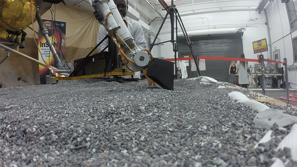Animated view of a replica of InSight scraping soil with a scoop