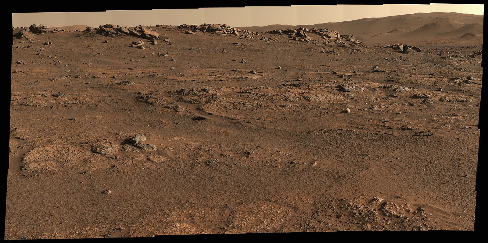 This is a colored image of the rocky, sandy surface of Mars. Large rocks and hills can be seen further away. Closer up rocks are embedded in the surface. This panorama is seen here in natural color (Figure 1) and enhanced color (Figure 2).