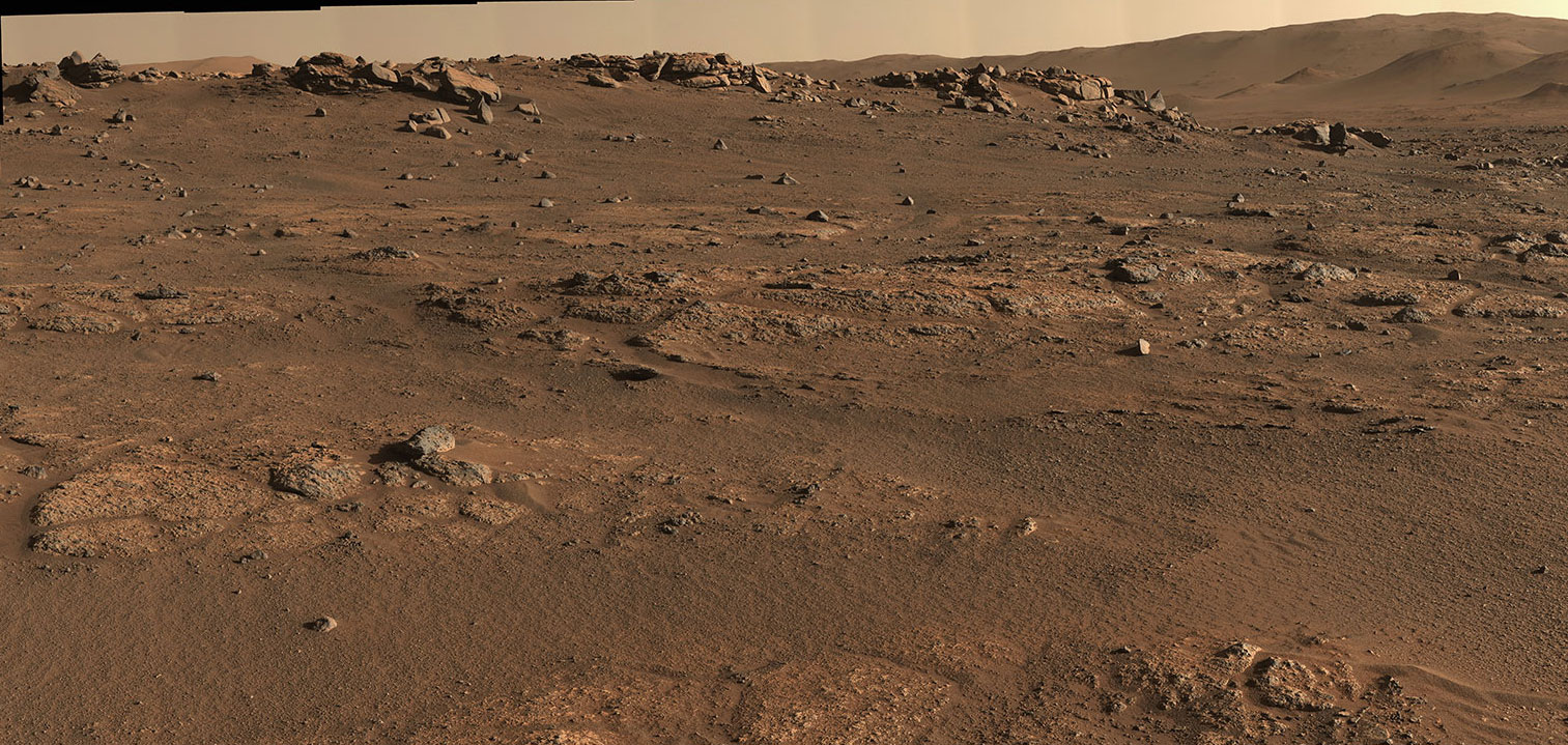 This is a colored image of the rocky, sandy surface of Mars. Large rocks and hills can be seen further away. Closer up rocks are embedded in the surface. This panorama is seen here in natural color (Figure 1) and enhanced color (Figure 2).