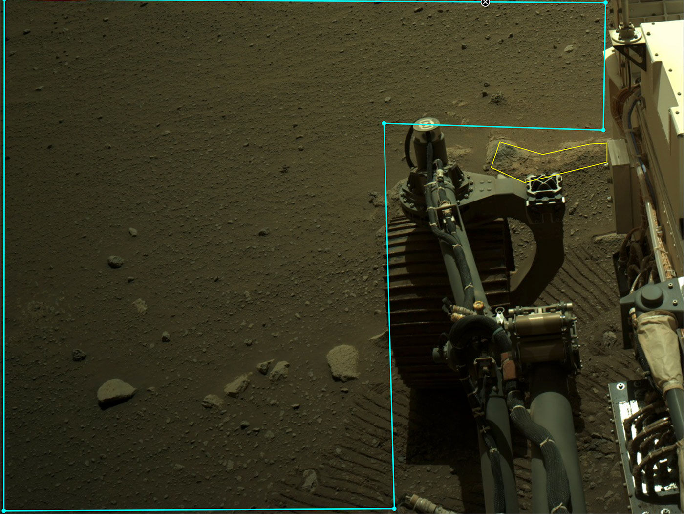 This is an annotated image of Perseverance's robotic arm and an outlined area in AI4Mars. The rover is positioned to the right and wheel tracks and the rocky, sandy surface of Mars are visible in the background.